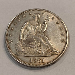 May include: Silver United States Half Dollar coin with the date 1861. The coin features a seated Liberty figure holding a staff and a shield with the inscription "LIBERTY".