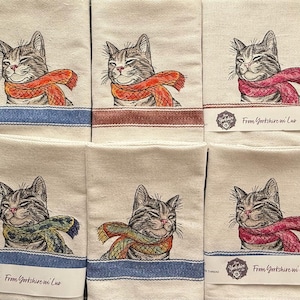 Gato con bufanda y paño de cocina