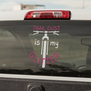 Puede incluir: Camioneta blanca con una calcoman&iacute;a rosa y blanca en la ventana trasera que dice "Trail Dust is my Glitter" con una silueta de una bicicleta.