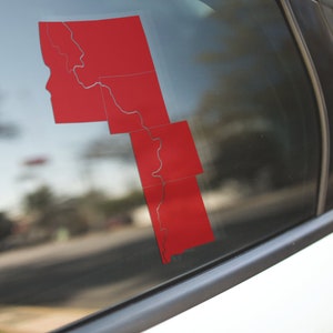 May include: A red vinyl sticker of a state outline on a car window.