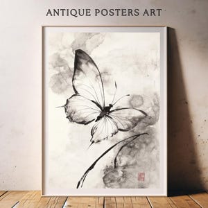 May include: Framed black and white butterfly art print. The artwork features a detailed butterfly with outstretched wings, set against a soft, watercolor-like background. The words "ANTIQUE POSTERS ART" are printed at the top.
