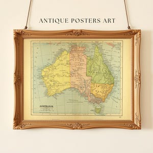 Puede incluir: Mapa antiguo enmarcado de Australia en un marco dorado ornamentado. El mapa está en tonos de amarillo, verde y rosa, con la palabra "AUSTRALIA" en la parte inferior. El texto "ANTIQUE POSTERS ART" está en la parte superior.