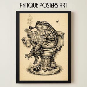 May include: Black framed art print featuring a whimsical illustration of a frog smoking a pipe while reading a newspaper on a toilet. The print includes the text "Antique Posters Art". A fly hovers nearby.