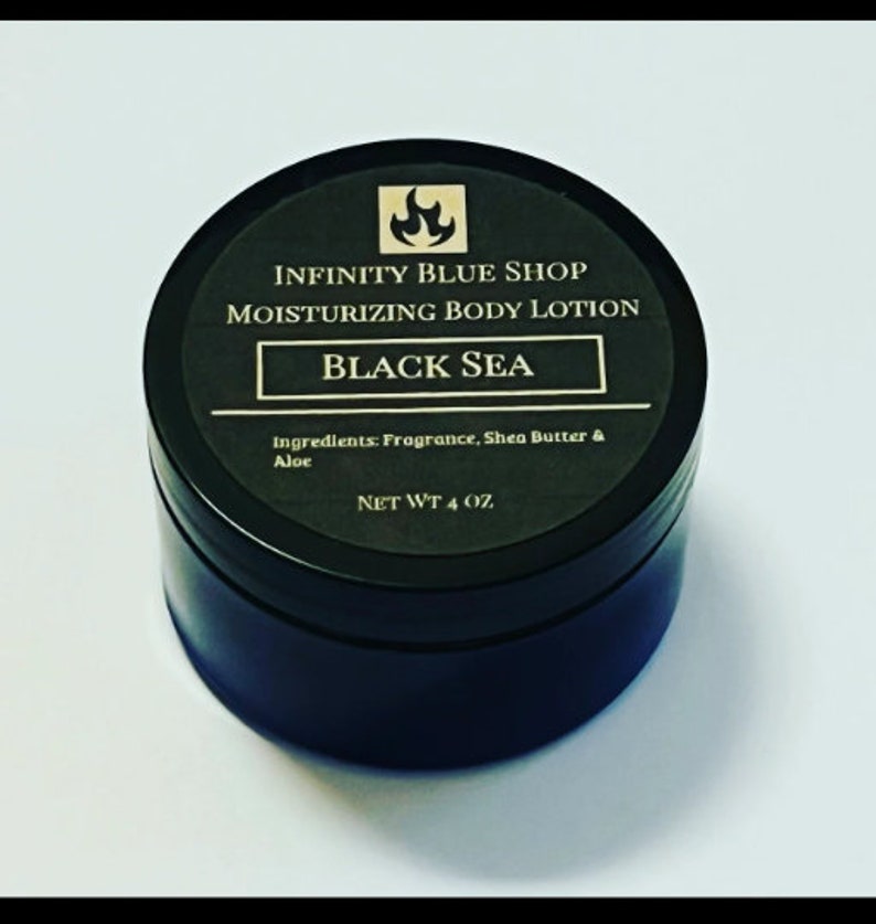 May include: A round black container of Infinity Blue Shop Moisturizing Body Lotion in the scent Black Sea. The label features a flame icon, lists ingredients as fragrance, shea butter, and aloe, and states a net weight of 4 oz on the lid.
