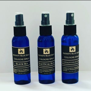 May include: Three blue glass bottles with black spray tops and gold labels. The labels read "Infinity Blue Shop Cologne Spray" with different scents: "Black Sea", "Nautical Bleu", and "Sandalwood & Citrus". Each bottle contains 2 oz of cologne.