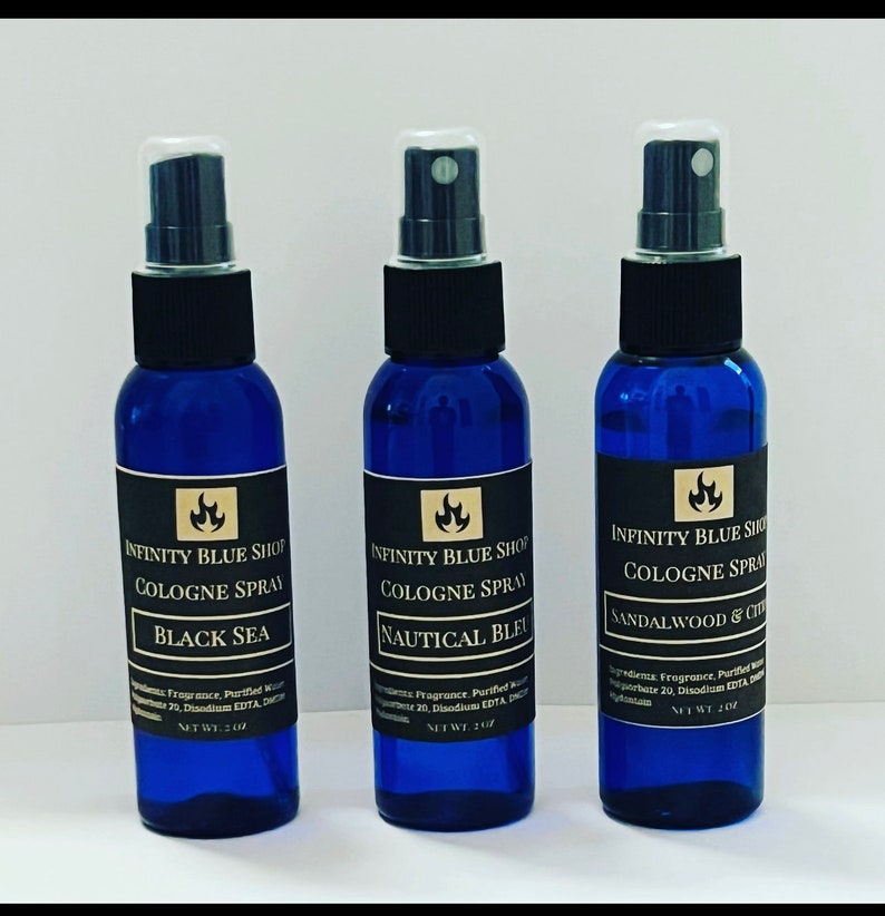 May include: Three blue glass bottles with black spray tops and gold labels. The labels read "Infinity Blue Shop Cologne Spray" with different scents: "Black Sea", "Nautical Bleu", and "Sandalwood & Citrus". Each bottle contains 2 oz of cologne.