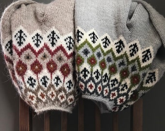 May include: Two knitted sweaters with geometric patterns in shades of brown, gray, white, green, and red. The sweaters are folded and draped over a wooden chair.
