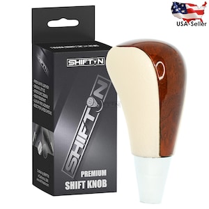 May include: A brown and beige leather car shift knob with a chrome base. The knob is packaged in a black box with the text "SHIFTIN PREMIUM SHIFT KNOB" printed on it.