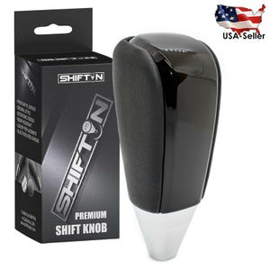 May include: A black and silver premium shift knob with a glossy finish and a textured leather grip. The product is in a black box with the brand name "SHIFTIN" and product details. The box also has the text "PREMIUM SHIFT KNOB".