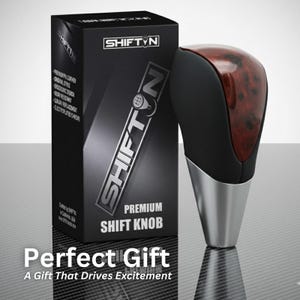 May include: A premium shift knob with a black and wood grain design, and a silver base. The product is packaged in a black box with the brand name "SHIFTN" in silver. The box also includes the text "Premium Shift Knob". The text "Perfect Gift" is also visible.