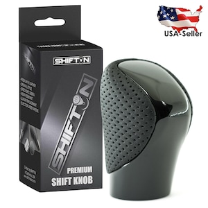 May include: A black shift knob with a perforated grip area and a glossy finish. The product is packaged in a black box with the "SHIFT N" logo and the words "PREMIUM SHIFT KNOB". The box also lists features like "premium PU leather".
