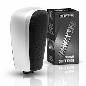 May include: A silver and black premium shift knob with a perforated grip. The product is displayed next to its black box packaging, which features the brand name "SHIFTYN" in white lettering.