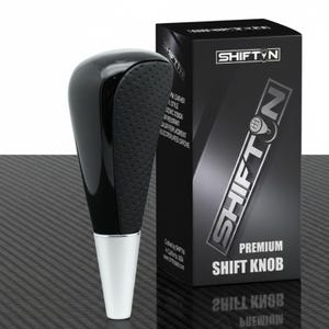 May include: A black and silver premium shift knob with a glossy finish and a textured grip. The product is next to a black box with the brand name "SHIFT N" in silver lettering. The box also says "PREMIUM SHIFT KNOB".