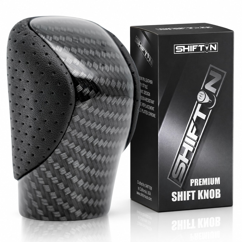 May include: A gear shift knob featuring a carbon fibre pattern and black perforated leather side panels. Next to it stands a black rectangular product box labelled SHIFTON Premium Shift Knob with a graphic of a gear pattern on the letter O.
