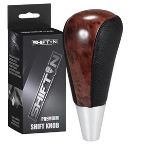 May include: A premium shift knob with a wood grain top and black leather sides. The knob has a chrome base and is packaged in a black box with the text "SHIFT N" and "PREMIUM SHIFT KNOB".