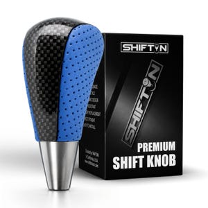May include: A gear shift knob featuring a black carbon fiber pattern on the top and sides, contrasted with blue perforated material on the front and back. The base is a smooth silver metal. It is displayed next to a black box labeled SHIFTIN.