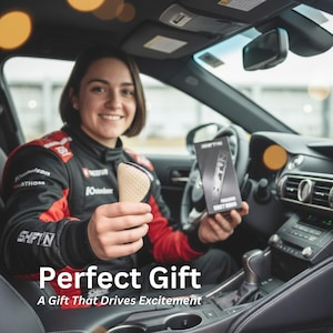 May include: A beige and silver car shift knob is held by a person in a race car driver's uniform. The text "Perfect Gift" and "A Gift That Drives Excitement" are displayed at the bottom of the image. A box with the text "SHIFT KNOB" is also visible.