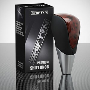 May include: A premium shift knob with a black and wood grain top and a silver base. The box next to it is black with the brand name "SHIFTN" in silver. The box also says "PREMIUM SHIFT KNOB".