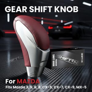 May include: A gear shift knob with a burgundy leather top and a silver base. The text "GEAR SHIFT KNOB" is at the top. The box next to it says "SHIFT KNOB PREMIUM" and "SHIFT N". The text "For MAZDA" and car model compatibility are at the bottom.