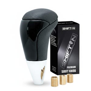 May include: A black gear shift knob with a textured top, a glossy black side panel, and a silver base. Next to it is a black box labeled SHIFTN PREMIUM SHIFT KNOB and three small gold-colored threaded metal adapters for installation.