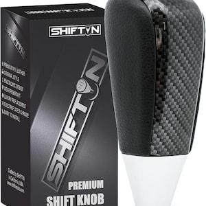 May include: A premium shift knob with a carbon fiber and black leather design. The knob has a white base and is next to a black box with the text "SHIFTIN" and "PREMIUM SHIFT KNOB".