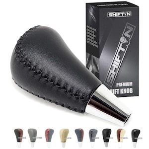 May include: Black leather gear shift knob with chrome accents and stitching. The knob is a replacement for a car's gear shifter. The product packaging is in the background and says "Shift'n Premium Shift Knob".