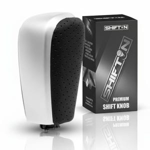 May include: A silver and black premium shift knob with a perforated grip. The product is displayed next to its black box packaging, which features the brand name "SHIFTYN" in white lettering.