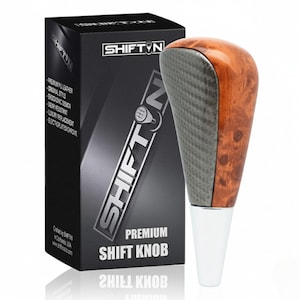 May include: A premium shift knob with a wood grain and carbon fiber design. The shift knob has a chrome base and is packaged in a black box with the text "SHIFT N" and "PREMIUM SHIFT KNOB".