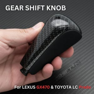 May include: A carbon fiber gear shift knob with the text "GEAR SHIFT KNOB" at the top. The bottom of the knob is black. The text "For LEXUS GX470 & TOYOTA LC Prado" is at the bottom.