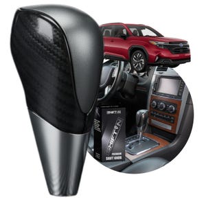 May include: A gear shift knob featuring a black carbon fiber textured upper section and a smooth, metallic silver base. The product is displayed alongside a box labeled SHIFTON PREMIUM SHIFT KNOB, a vehicle interior console, and a red SUV.