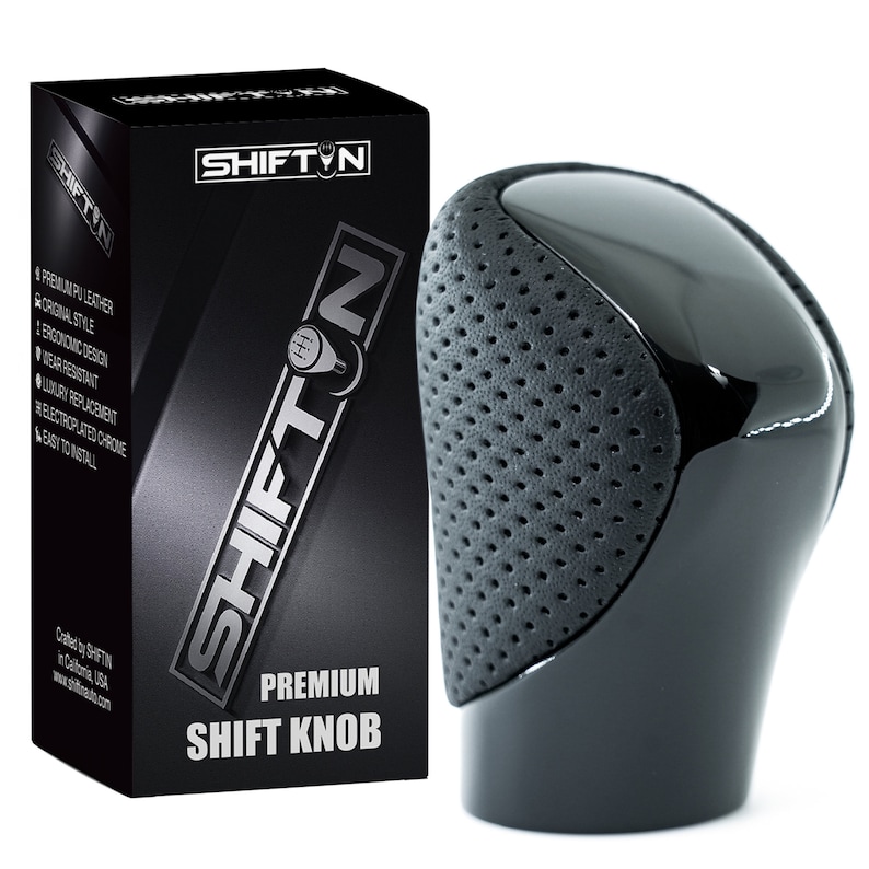 May include: A black gear shift knob featuring a smooth, glossy top section and a textured, perforated grey side panel. The product is displayed next to its black retail box, which is labelled with the brand name SHIFTIN and the text PREMIUM SHIFT KNOB.