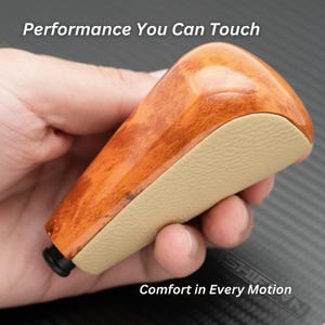 May include: A car gear shift knob with a wood grain finish and a tan leather-like grip. The text "Performance You Can Touch" and "Comfort in Every Motion" are visible.