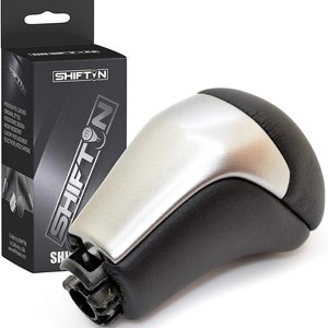 May include: A black and silver car shift knob with a leather grip and a metallic silver top. The product is packaged in a black box with the brand name "SHIFT N" in white lettering.