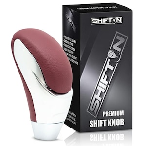 May include: A premium shift knob with a burgundy leather top and a chrome base. The product is packaged in a black box with the brand name "SHIFT N" and product details. The shift knob has an ergonomic design.