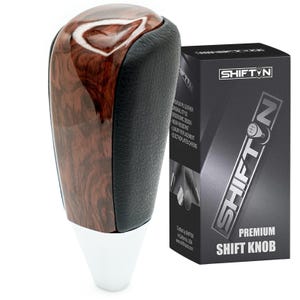 May include: A premium shift knob with a wood grain finish, black leather accents, and a white base. The product is packaged in a black box with the "SHIFTYN" logo and the words "PREMIUM SHIFT KNOB".