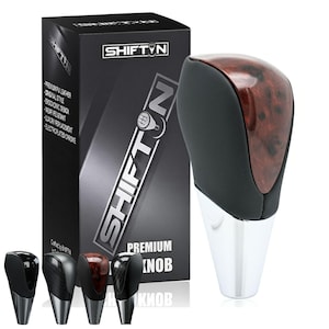 May include: A premium shift knob with a wood grain top and black leather sides, and a chrome base. The product is displayed with its packaging, which features the brand name SHIFT'N and the words "PREMIUM KNOB".