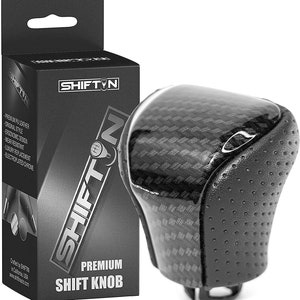 May include: Black leather shift knob with a carbon fiber pattern and a chrome accent. The knob is packaged in a box with the brand name "SHIFTIN" printed on it.