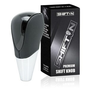 May include: A black and white shift knob with a glossy finish. The shift knob is next to a black box with the text "SHIFTN" and "PREMIUM SHIFT KNOB". The box also lists features like "PU Leather Style" and "Chrome Plated Chrome".