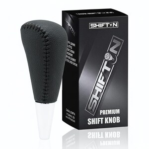 May include: A black leather shift knob with white base and a black box. The shift knob is made of TPU leather and has a stitched design. The box has the text "SHIFT N" and "PREMIUM SHIFT KNOB".
