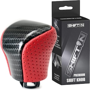 May include: A black and red carbon fiber and leather shift knob with a perforated leather design. The knob is packaged in a black box with the text "SHIFT'N PREMIUM SHIFT KNOB".