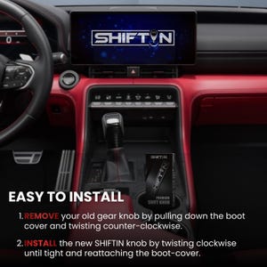 May include: A black gear shift knob with a carbon fibre texture installed in a vehicle centre console with red trim. The infotainment screen displays the SHIFT-N logo. A black product box labelled SHIFT-N PREMIUM SHIFT KNOB sits in the cup holder.