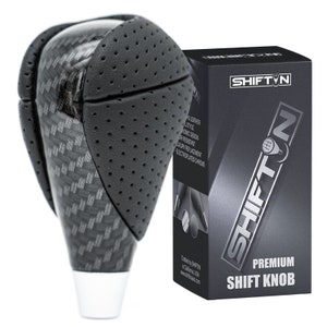 May include: Black carbon fiber and leather shift knob with a silver base. The knob has a perforated leather design and a chrome accent. The packaging says "Shift'n Premium Shift Knob".