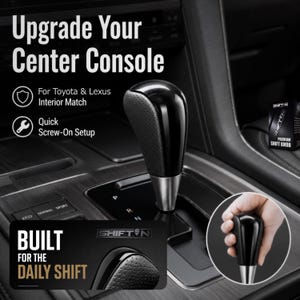 May include: A black gear shift knob with a perforated leather-like texture on the side and a smooth top, featuring a silver metallic base. The knob is installed in a vehicle center console with text reading Upgrade Your Center Console.