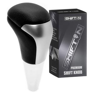 May include: A black and silver shift knob with a white base, next to a black box with the text "SHIFT N" and "PREMIUM SHIFT KNOB". The shift knob has a leather-like texture and a chrome-plated design.