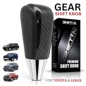 May include: A black gear shift knob with a carbon fiber texture and a silver metallic base. The product is displayed next to its black packaging box labeled SHIFTN PREMIUM SHIFT KNOB FOR TOYOTA & LEXUS, featuring images of four different vehicles.