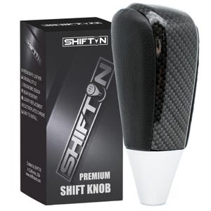 May include: A black and carbon fiber premium shift knob with a white base, next to a black box with the Shiftin logo and product details. The shift knob has a textured leather top.