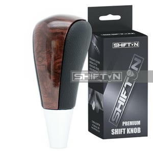 May include: A premium shift knob with a wood grain top and black leather grip. The knob has a white base and is next to a black box with the text "SHIFT N" and "PREMIUM SHIFT KNOB".