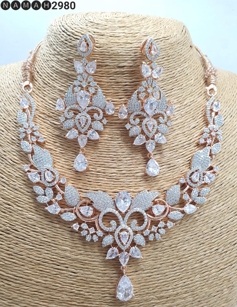 May include: A rose gold necklace and earrings set with a floral design and clear cubic zirconia stones.