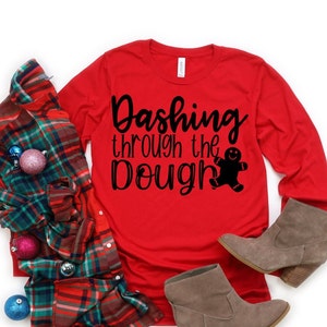 May include: Red long-sleeved shirt with the text "Dashing through the dough" and a gingerbread man graphic.