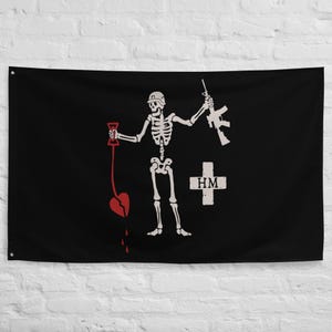 Könnte beinhalten: Schwarze Flagge mit einem weißen Skelett, das ein Gewehr und ein zerbrochenes Herz hält. Ein weißes Kreuz mit "HM" befindet sich auf der rechten Seite. Das Skelett befindet sich in der Mitte der Flagge.